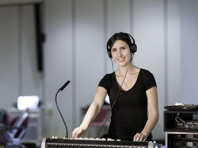 Junge Frau mit Kopfhörern an einem Mischpult beim Studiengang „Ton und Bild“ an der RSH Düsseldorf