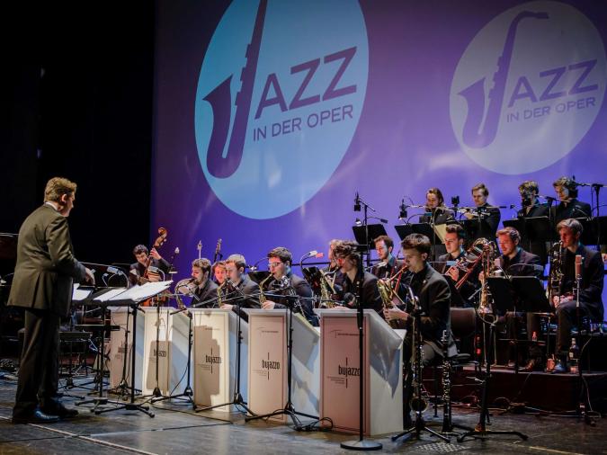 Bundesjazzorchester spielt auf Bühne vor Projektion „Jazz in der Oper“