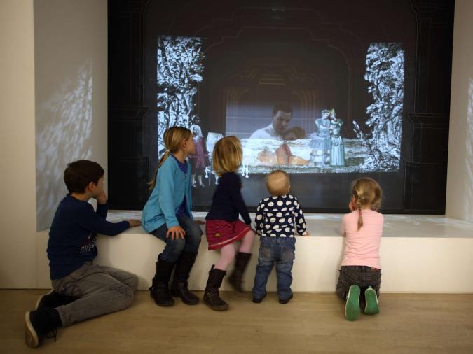 Fünf Kinder schauen sich eine Animation in einem Museum an.