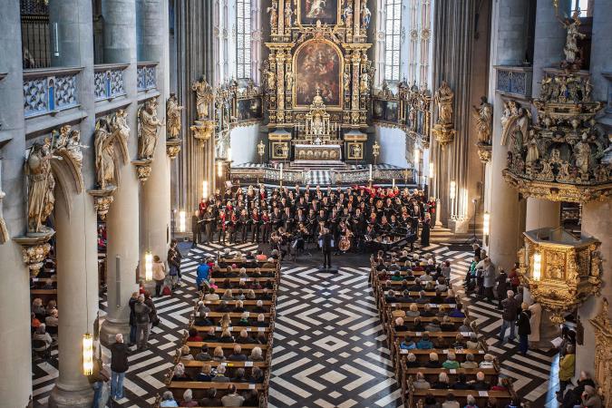 Blick auf den Chor einer vollbesetzten Kirche, in dem ein Orchester spielt.