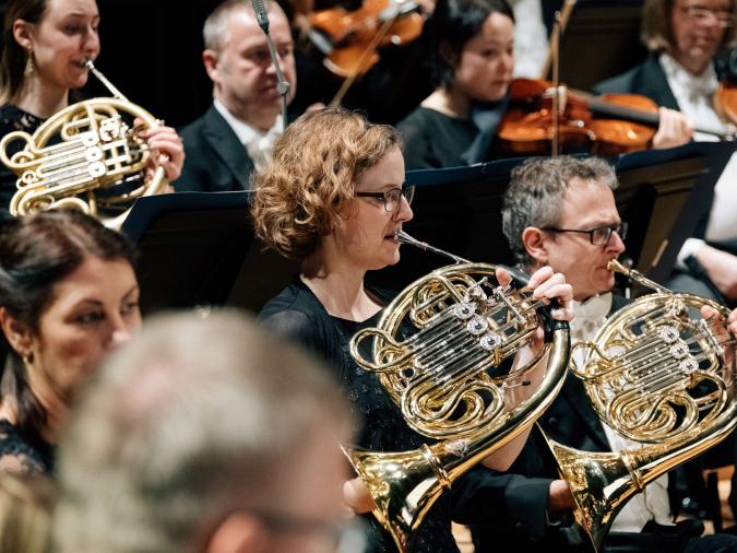 Weibliche und männliche Hornisten in einem Orchester