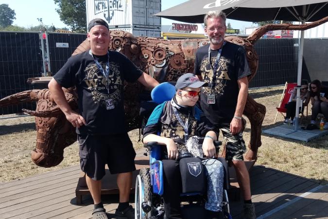 Bild: Fan im Rollstuhl mit zwei Buddies / Begleitpersonen auf dem Wacken Open Air