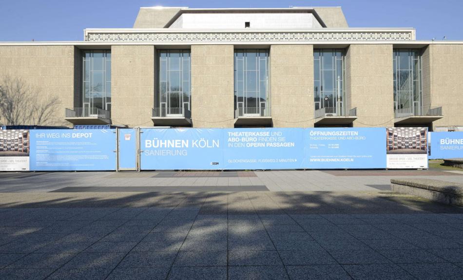 Aktuelle Außenansicht der Oper Köln mit Bauzaun.