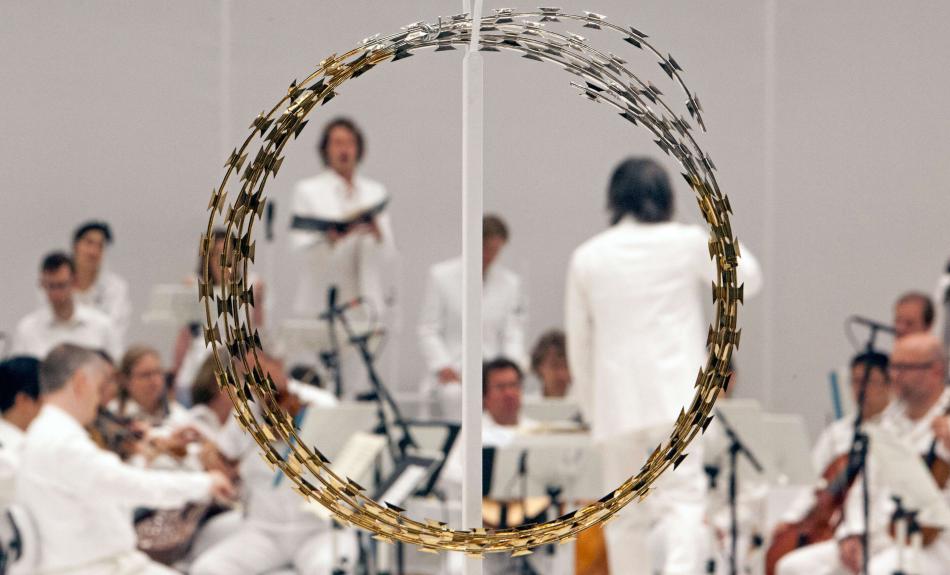 Während der Aufführung von "Las Passione" ist das Orchester ganz in weiß gekleidet. Im Vordergrund ist ein großer goldener Ring aus Draht positioniert, der an eine Dornenkrone erinnert.