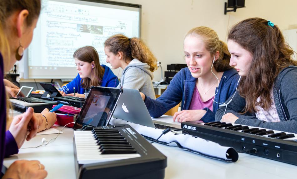 Mädchen mit Keyboards, Tablets und Kopfhörern in einem Klassenraum