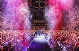 Die Hip-Hop-BAnd Die Fantastischen Vier stehen auf der Bühne, mit den Gesichtern zu einem riesigen Publikum. Links und rechts von der Bühne schießt rosafarbenes Confetti in die Höhe.