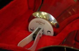 Glocke des Handglockenchors Bad Schandau. Das Instrument liegt in einem mit rotem Sand audgekleideten Glockenkasten.
