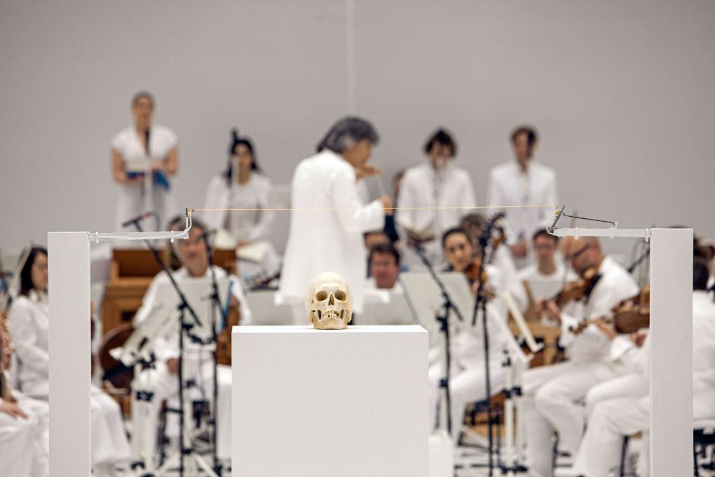 Bei der Inszenierung von "La Passione" an der Staatsoper Hamburg sind alle Beteiligten auf der Bühne ganz in weiß gekleidet. Im Vordergrund ist ein Schädel positioniert.