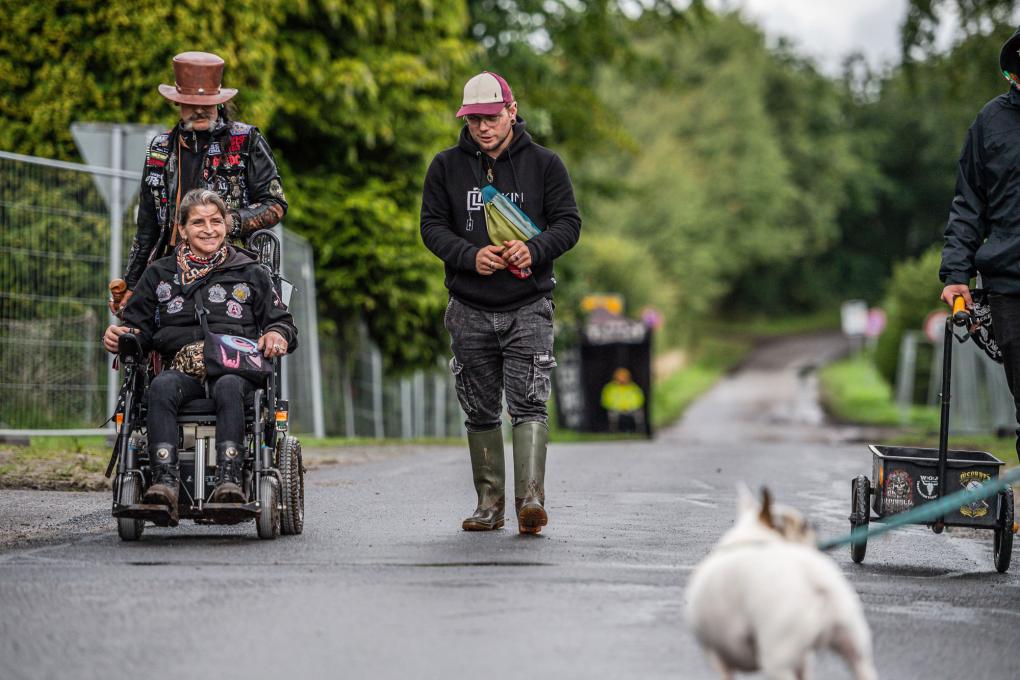 Bild: Fans auf dem Weg zum Wacken Open Air 2023, davon ein Fan im Rollstuhl