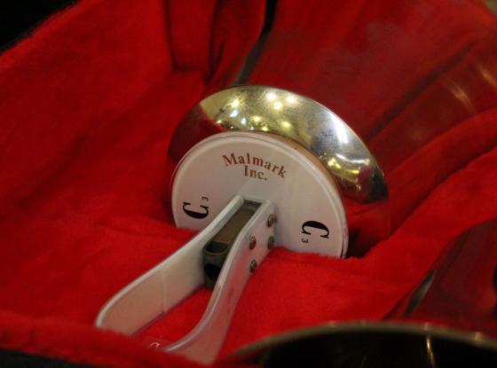 Glocke des Handglockenchors Bad Schandau. Das Instrument liegt in einem mit rotem Sand audgekleideten Glockenkasten.