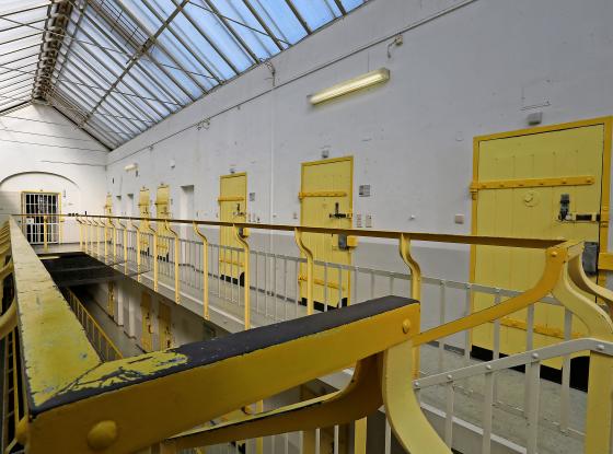 Foto eines Flurs im oberen Stockwerk eines Gefängnisses mit hellgelb gestrichenen Türen